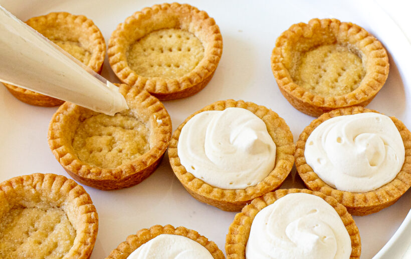 Piping filling into the tart shells.