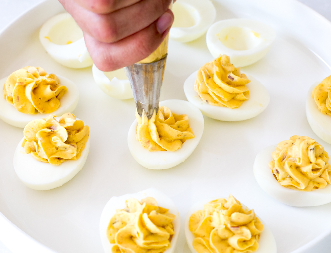 piping egg yolk mixture into eggs
