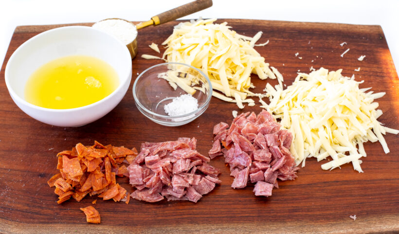 ingredients for pizza muffins on wooden cutting board