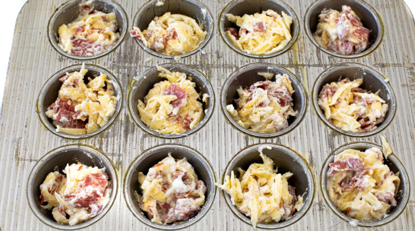 portioning pizza muffin dough into greased muffin tin