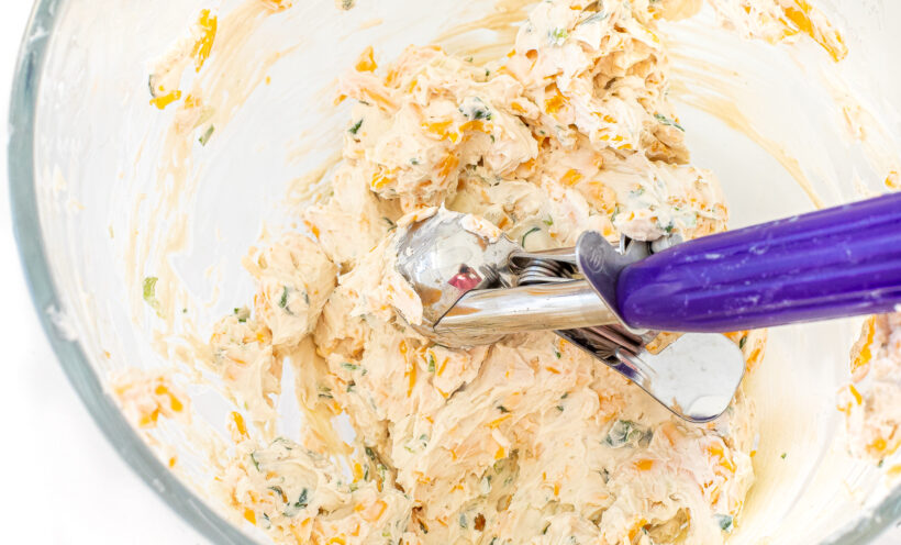 Cheese ball ingredients in a bowl with an ice cream scoop.