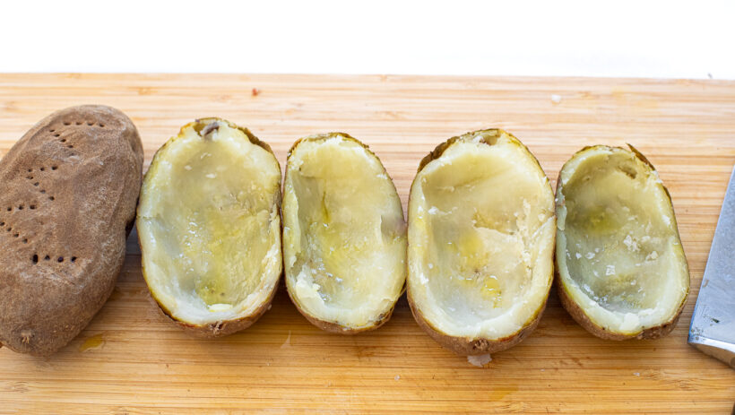 Potatoes cut in half with the centers scooped out. 