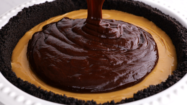 pouring chocolate ganache ontop of peanut butter layer