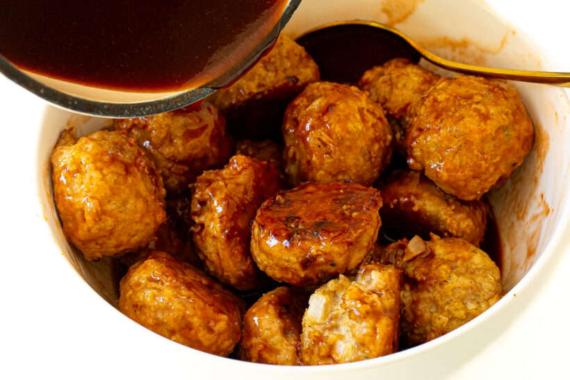 Pouring firecracker sauce over cooked meatballs.