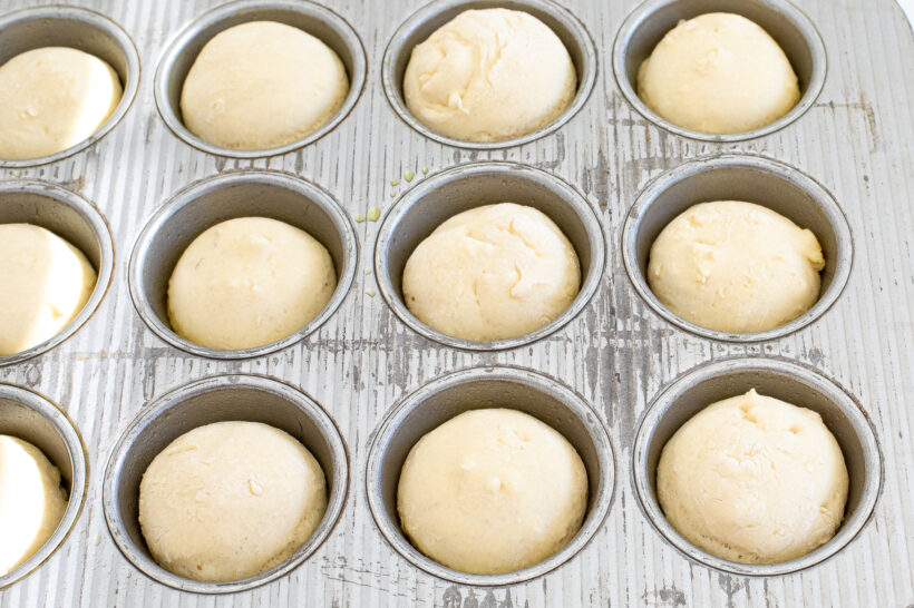 Focaccia dough in a muffin tin after the dough has proofed and risen.