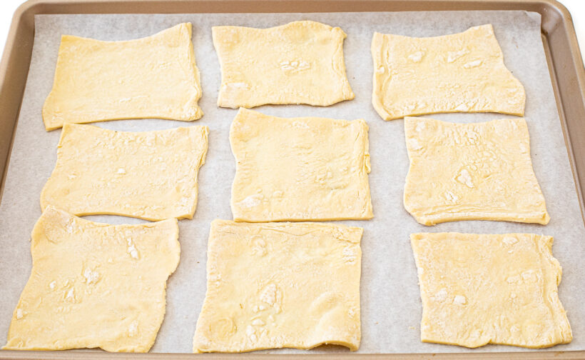 Puff pastry squares laid out on a baking sheet lined with parchment paper.