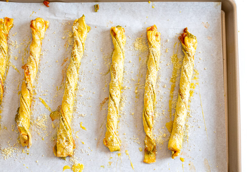 Pesto parmesan cheese straws assembled and placed on a baking sheet. 