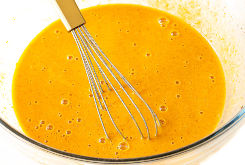 Custard in a mixing bowl with a whisk.