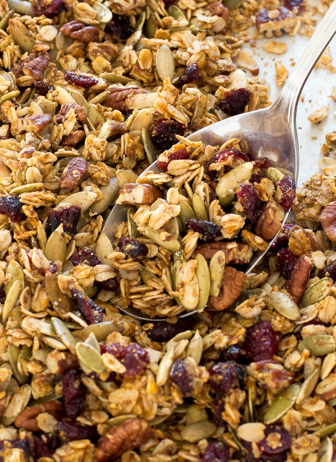 spooning pumpkin pecan granola on large sheet tray