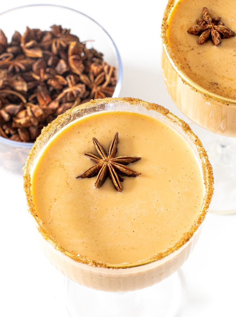 Sugar-rimmed glasses with pumpkin spice eggnog martinis, garnished with star anise.
