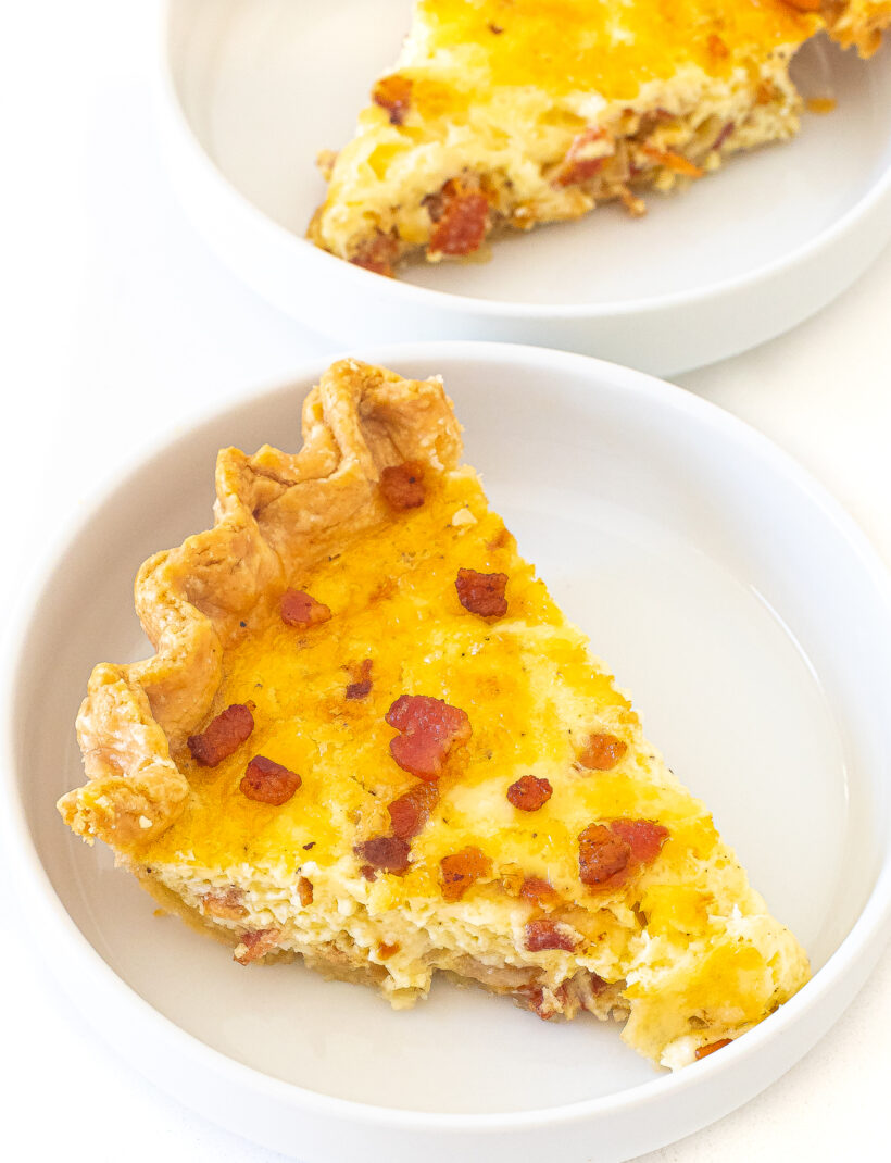 A slice of quiche lorraine on a white plate.