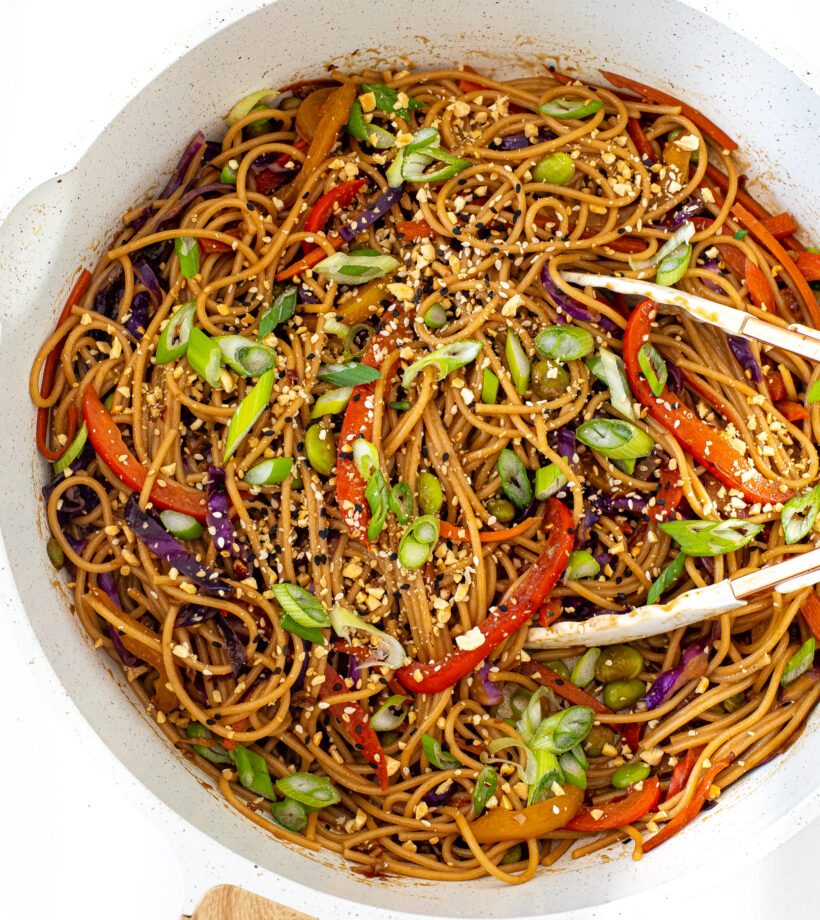 overhead shot of rainbow noodles in large saute pan with tongs