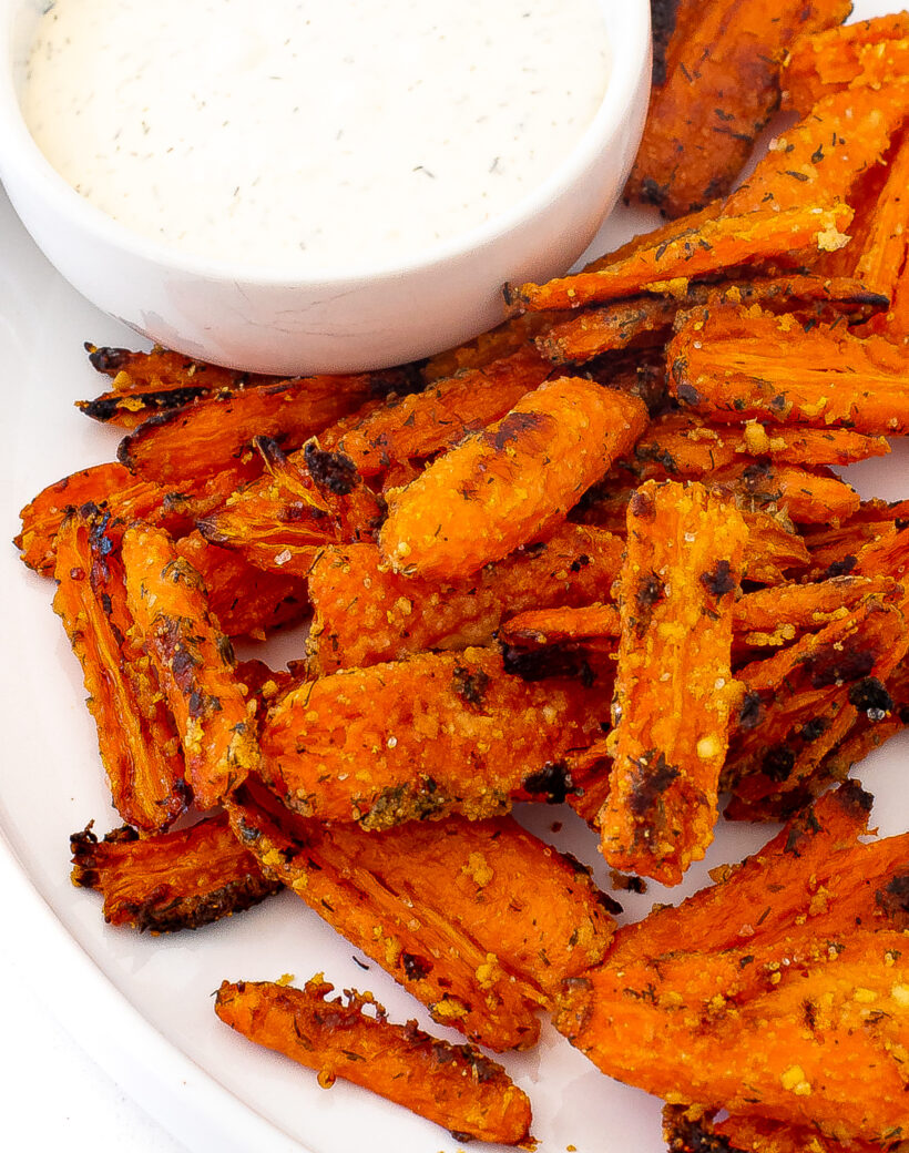 Crispy smashed carrots served on a plate next to a small bowl of ranch.