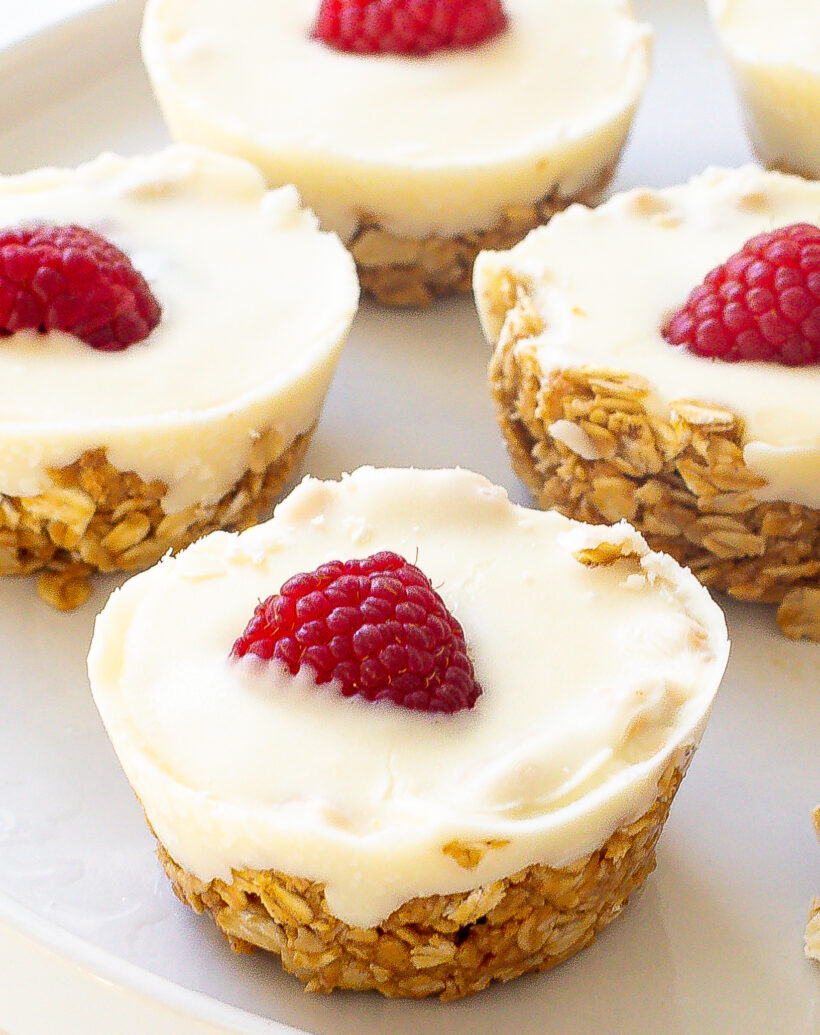 White chocolate oat cup with a raspberry on top served on a white plate.