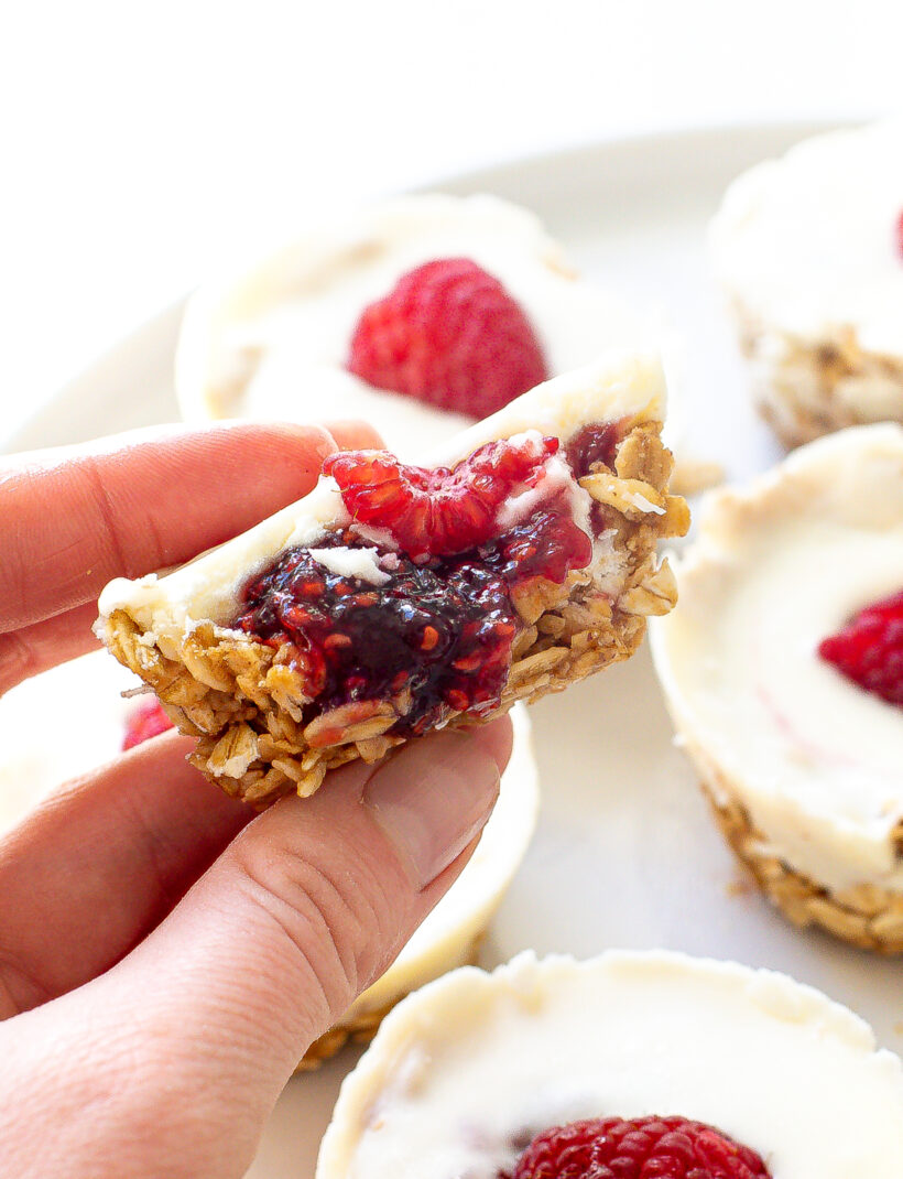 Hand holding an oat cup with a bite taken out of it to show the different layers.