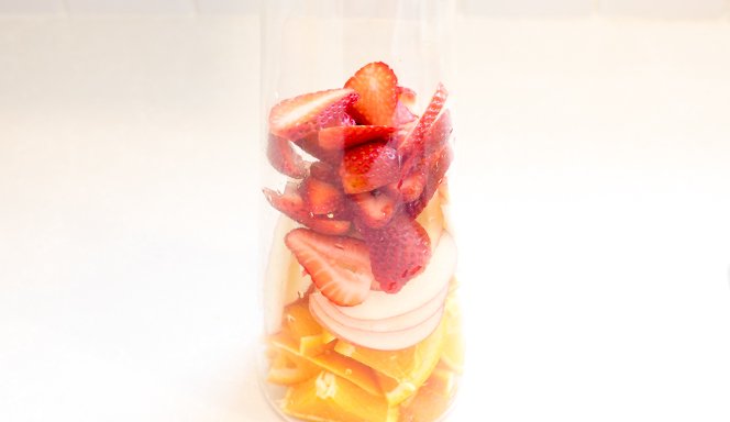 adding strawberries, apples and oranges to pitcher