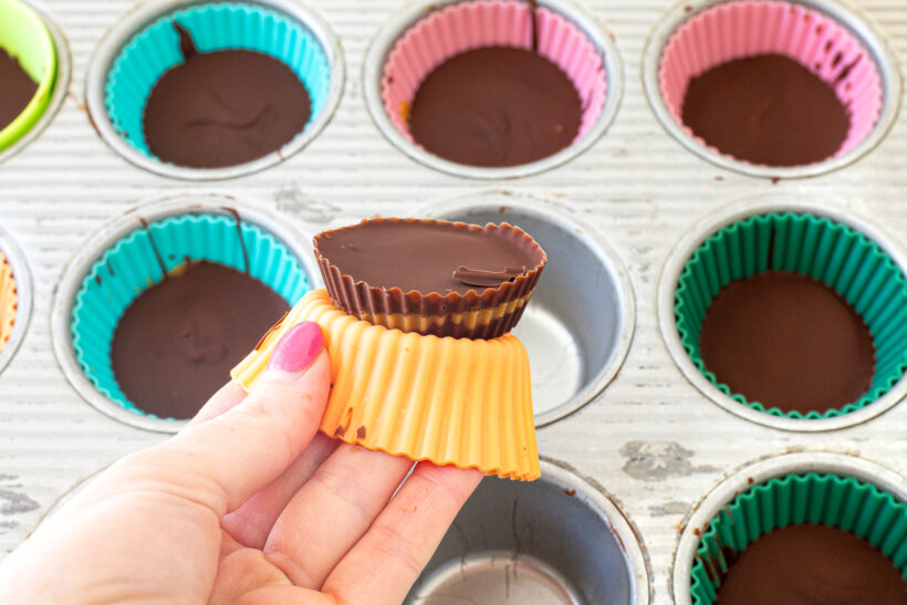 Hand pushing out a peanut butter cup from a silicon liner.