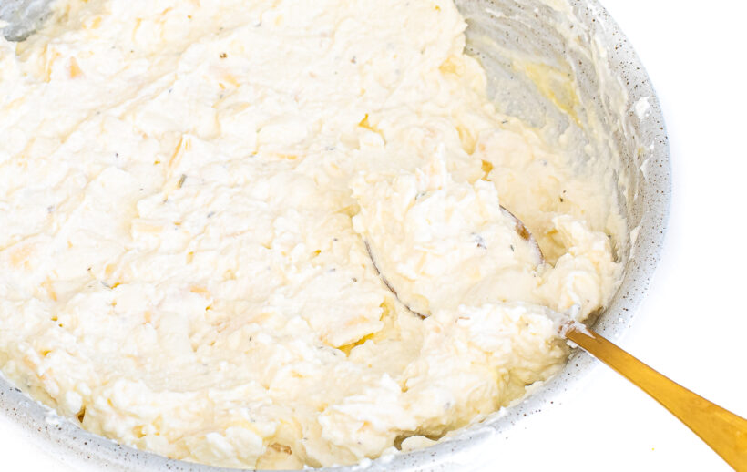 Ricotta filling in a bowl with a gold spoon.
