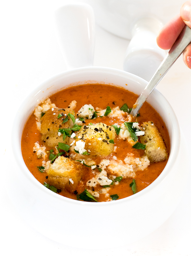 Creamy Roasted Red Pepper and Tomato Soup in a white bowl garnished with croutons, parsley, and feta cheese | chefsavvy.com