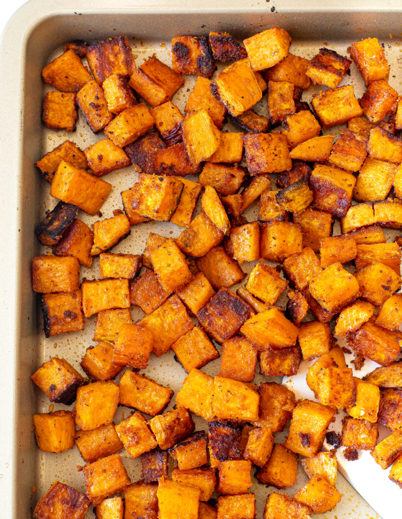 Overhead shot of roasted sweet potatoes in a sheet pan.