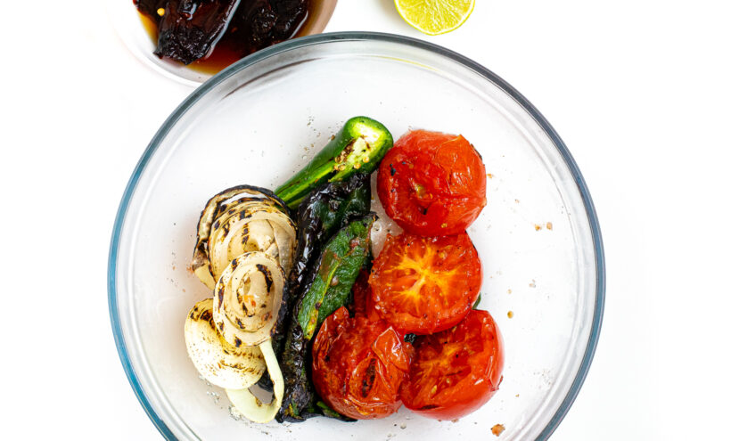 Roasted veggies for salsa in a glass mixing bowl.