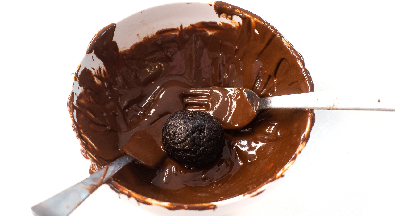 dipping truffle into melted milk chocolate