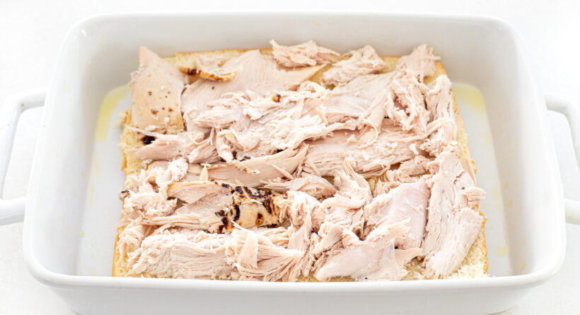 Turkey on top of bread in a baking dish.