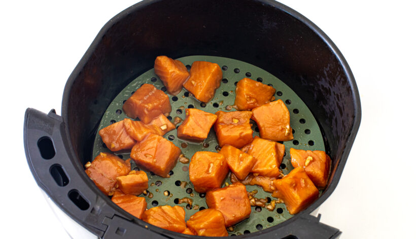 Cubes of salmon in an air fryer before being cooked. 