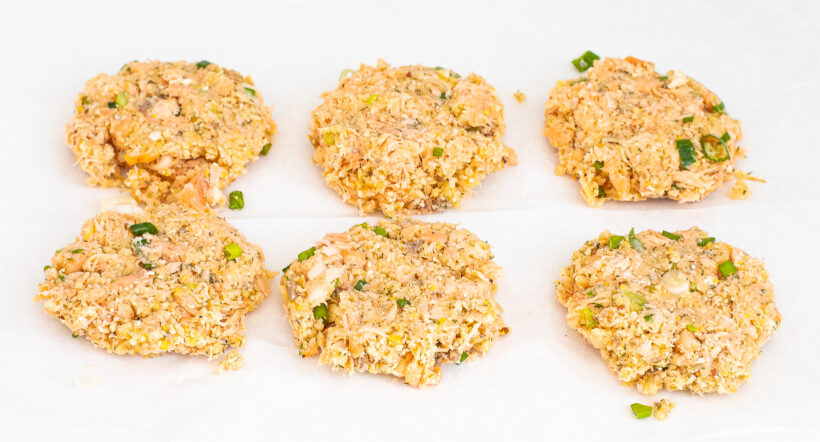 Uncooked salmon cakes on a baking sheet.