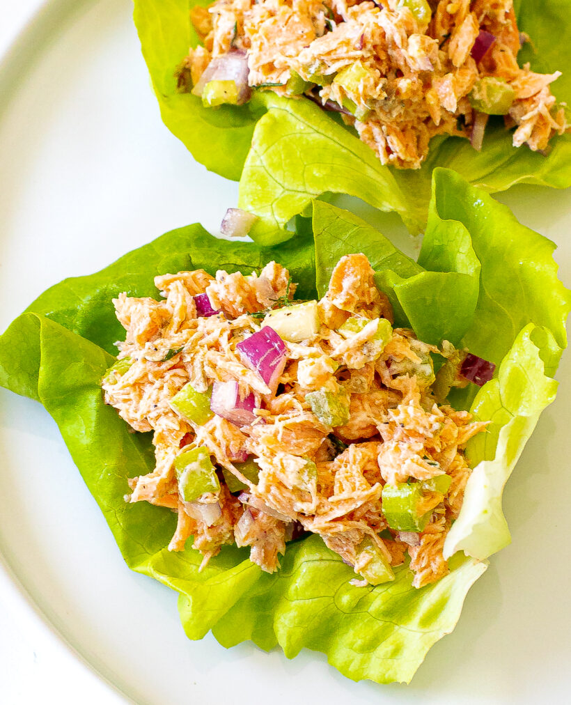 Salmon salad served in a lettuce cups on a white plate. 
