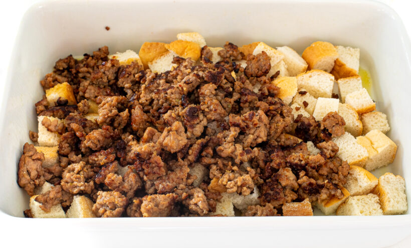 adding sausage and cubed bread to casserole