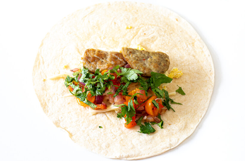 Tortilla laid out with filling ingredients on top.