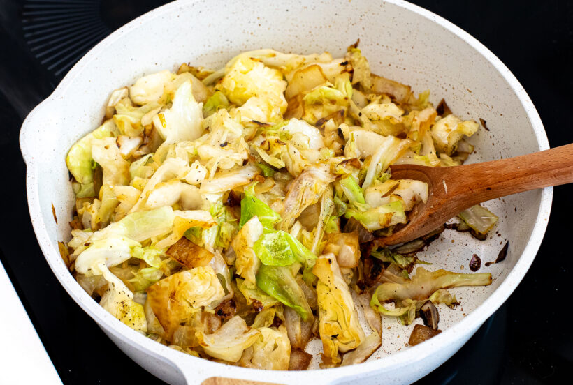 Cabbage cooking with onions and garlic in a skillet. 