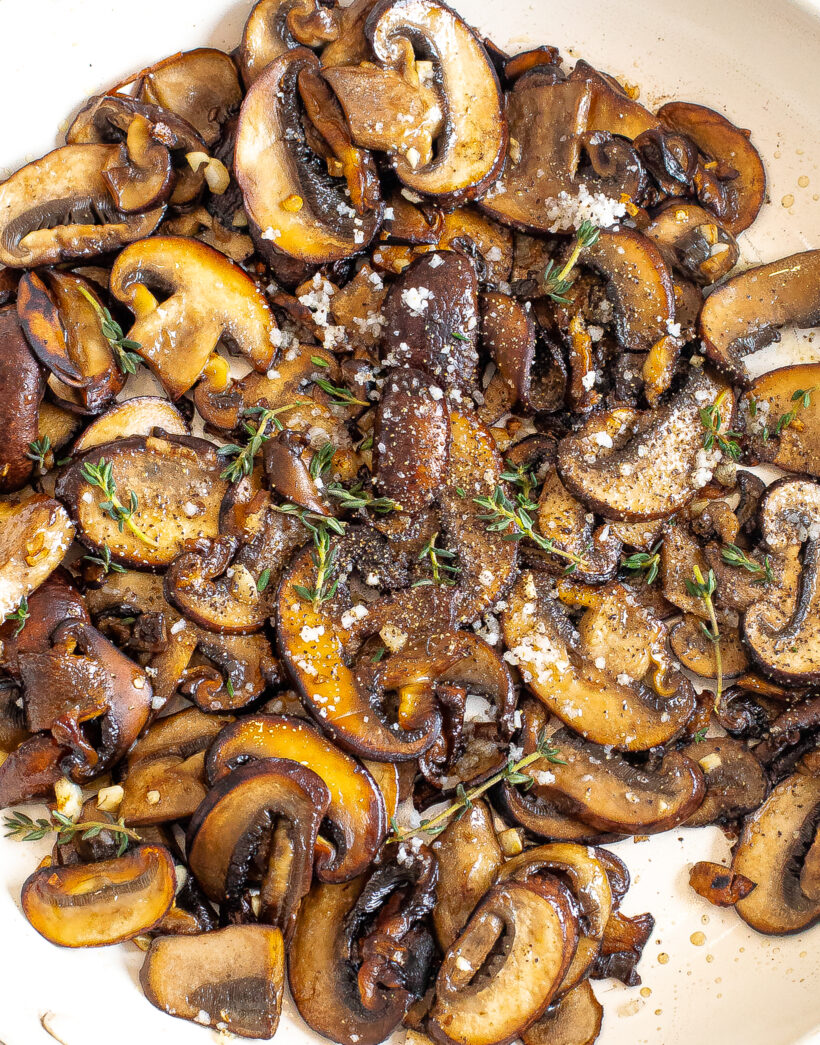 Sauteed mushrooms with garlic in a skillet topped with thyme.
