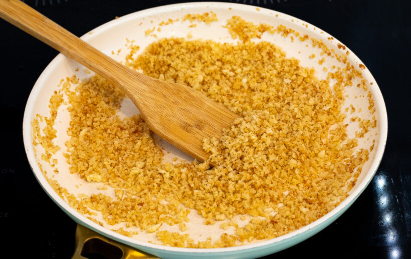 Bread crumbs in a skillet being toasted.