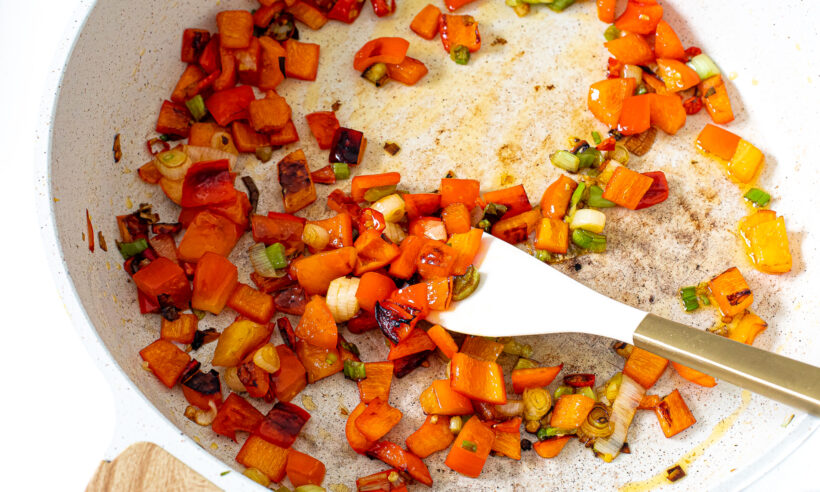 Cook veggies for fried rice in a white skillet.