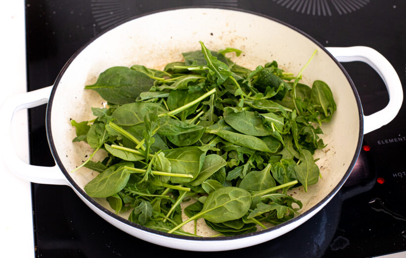 Spinach and arugula greens being cooked lightly in a skillet. 