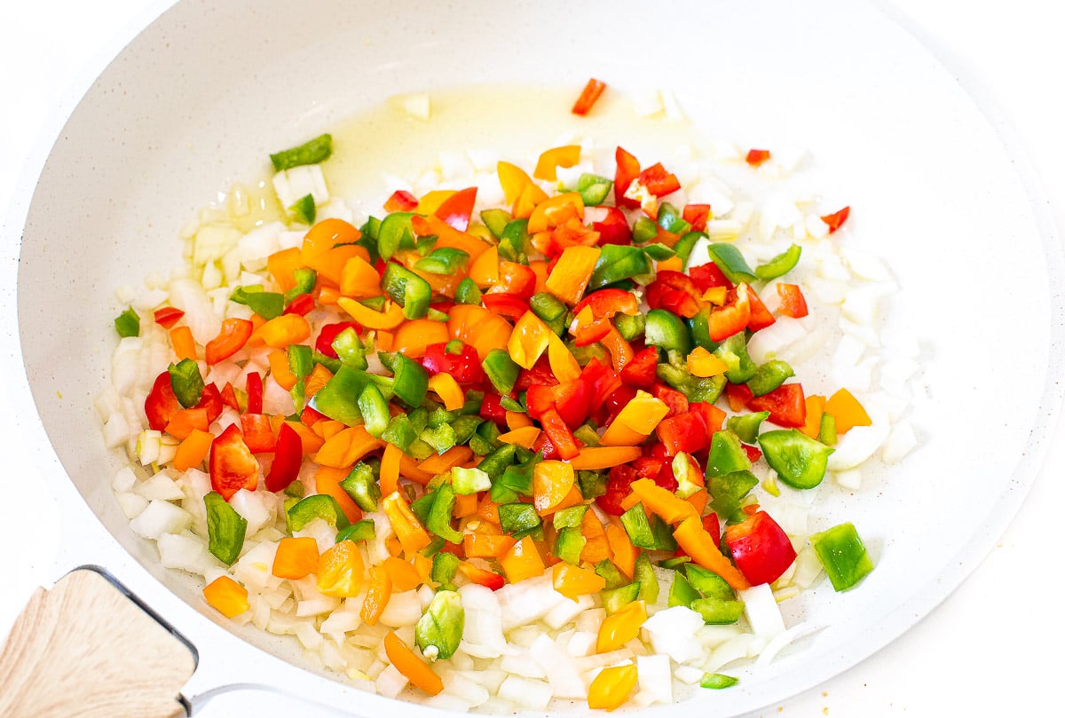 sautéing onions and diced bell peppers in a large skillet