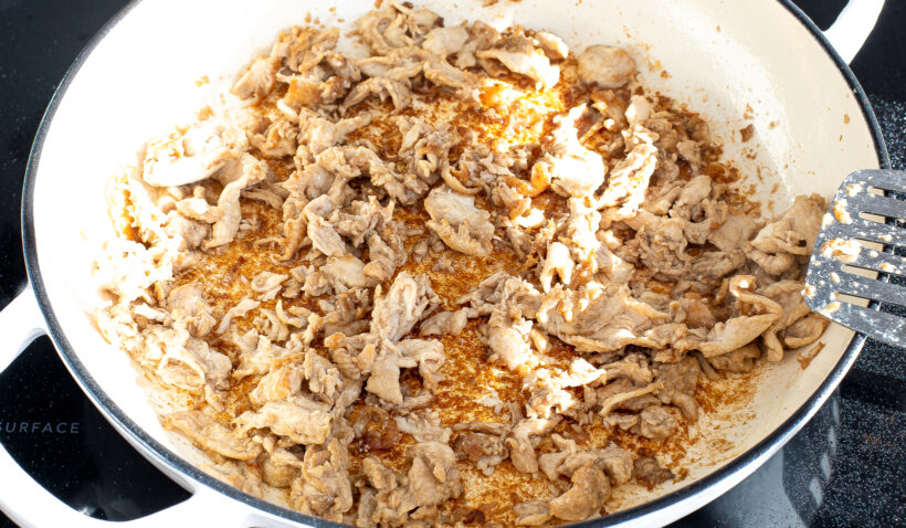 Chicken being sautéed in a skillet on the stove. 