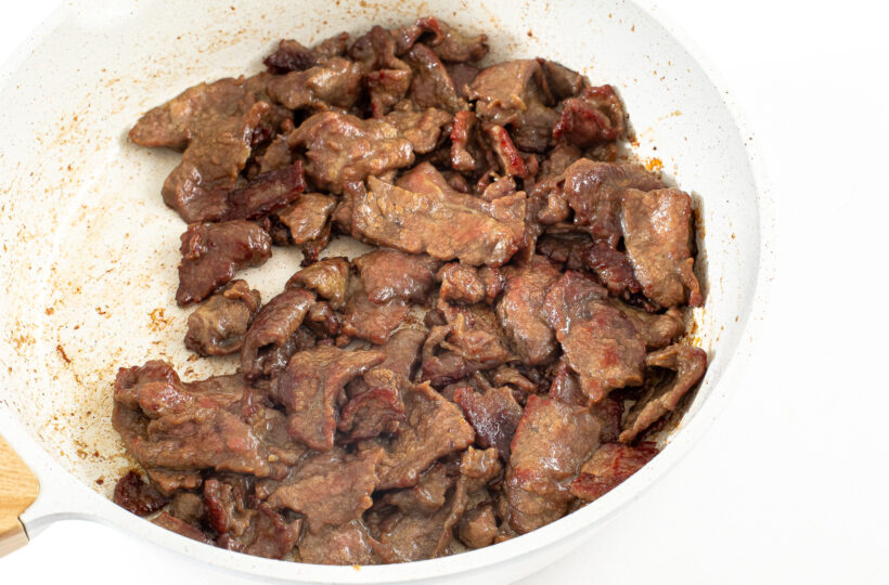 Cooked fank steak slices in a large skillet.