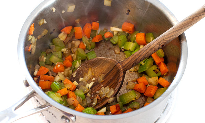 Celery, onion and carrots being sautéed in a saucepan.
