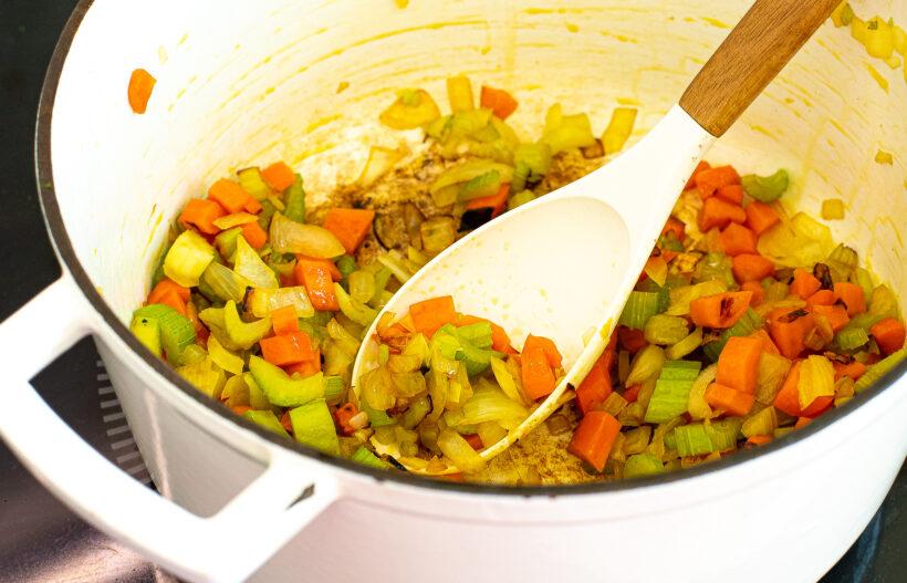 Veggies sautéing in a large pot.