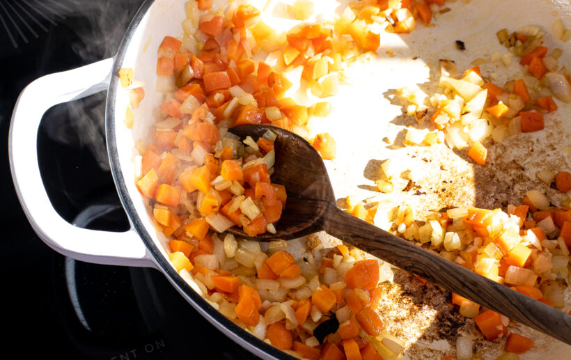 Carrots and onions being cooked in a skillet on the stove.