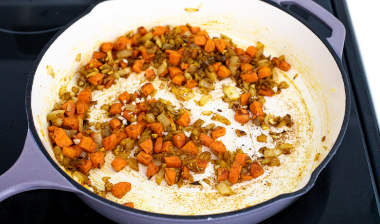 Carrots and onions being sautéed in a skillet. 