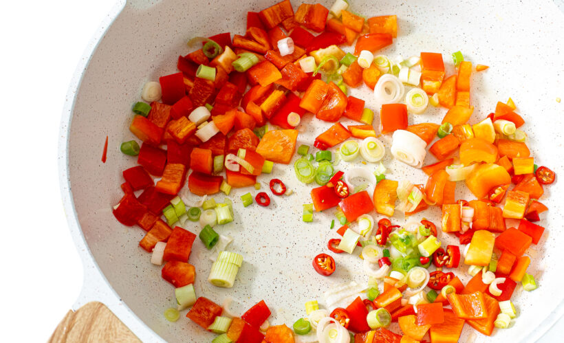 Veggies for fried rice in a white skillet.