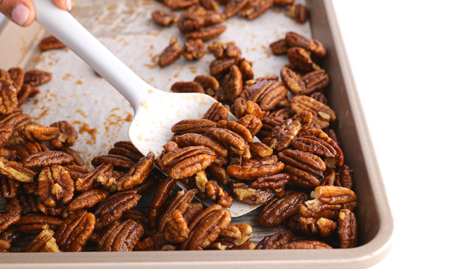 scooping nuts off of a baking sheet with a rubber spatula