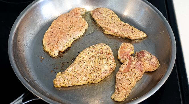 Lemon pepper chicken in a silver skillet. 