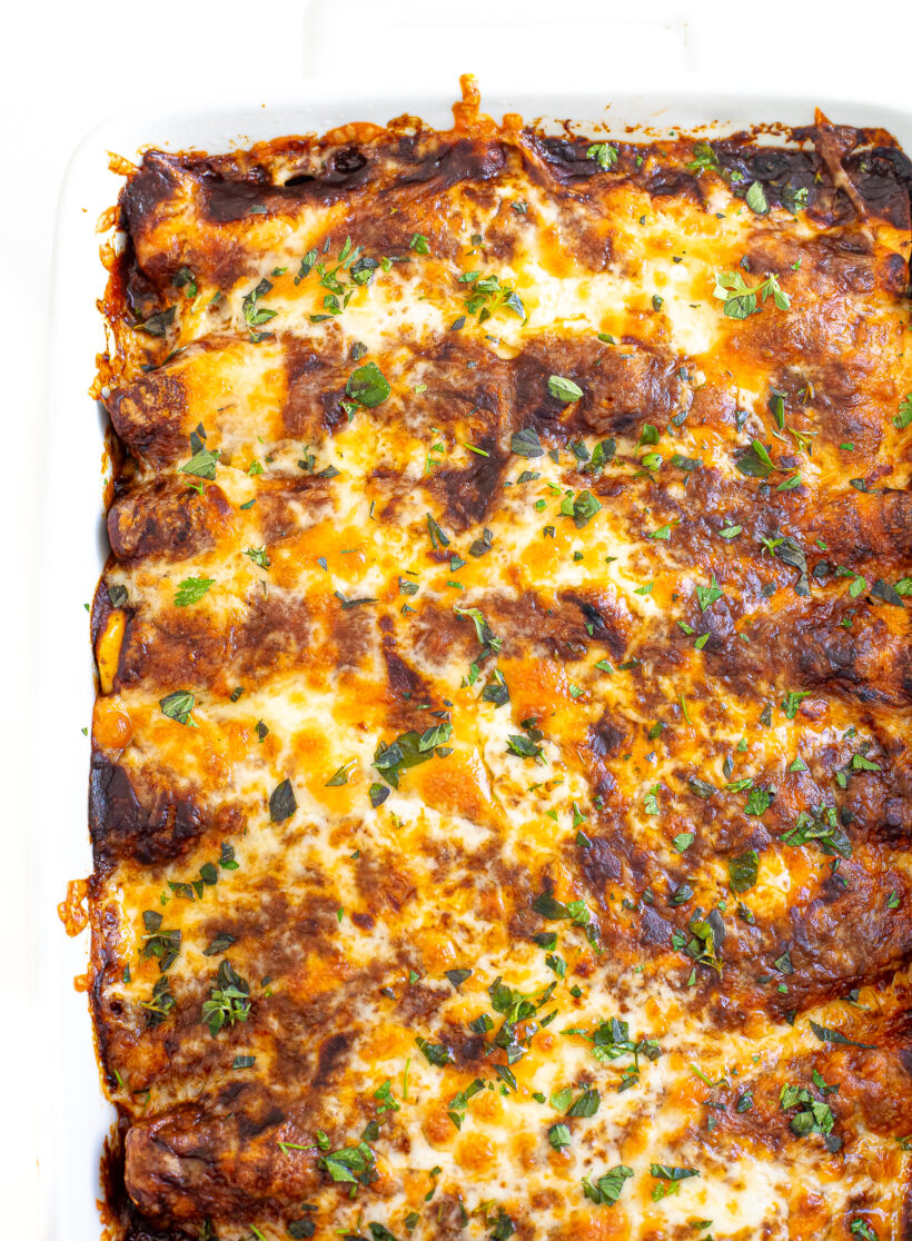 Baked enchiladas in a white baking dish.