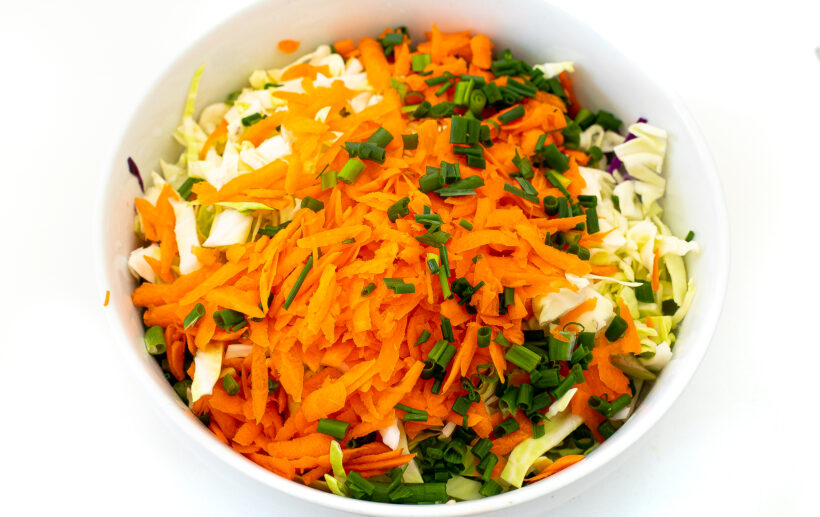 Cabbage, shredded carrots and scallions in a large bowl.