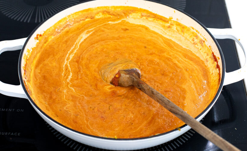 Butter curry sauce in a skillet with a wooden spoon. 